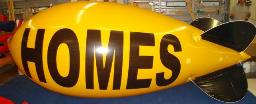 Helium Advertising Blimp - 17ft. blimp with HOMES for a home builder. Blimps can make an immediate impact with the traffic to your models or sales office.